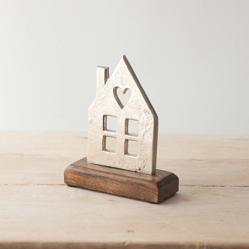 Simplistic house shaped aluminium plaque on a wooden base. Features a chimney and cutout windows and a heart shaped cutout in the roof. 