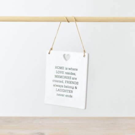 Ceramic rectangle hanging sign with the quote 'Home is where love resides, memories are created, friends always belong and laughter never ends'. Above the quote is a heart cut out from the sign. 