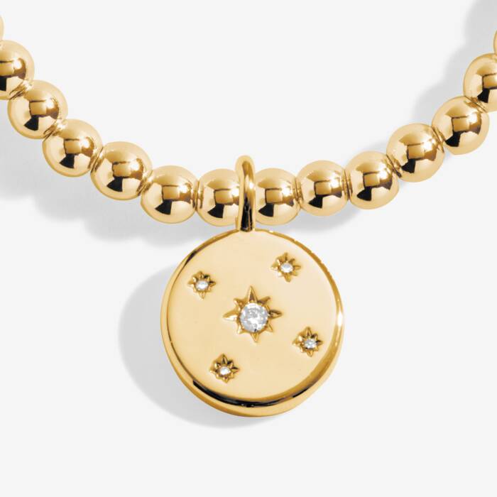 Gold necklace with a round pendant featuring star designs on a white background