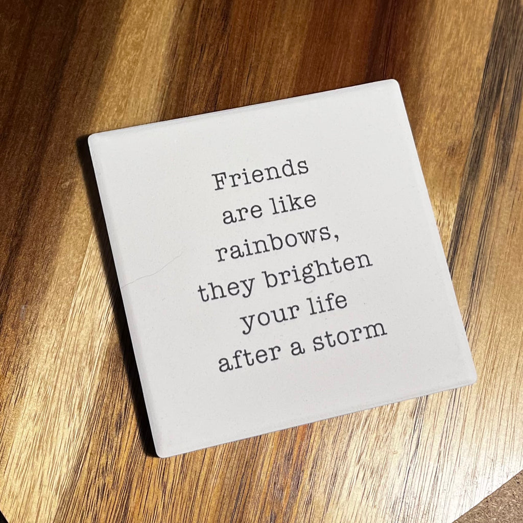 Square white coaster with the quote 'Friends are like rainbows, they brighten your life after a storm' in typewriter font