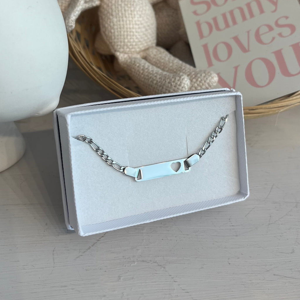 Silver chain bracelet with a silver bar in the middle. Silver bar features a cutout heart on the right with space for an engraving on the side. 
