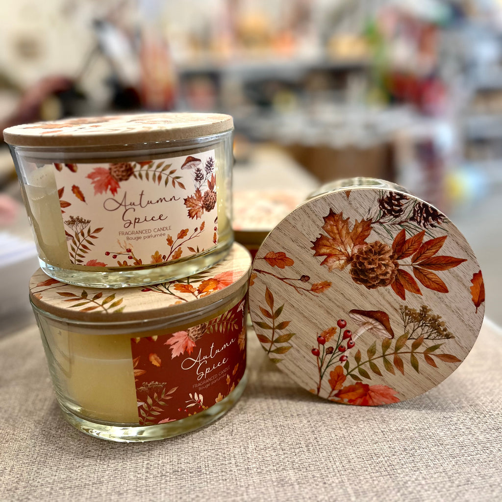 Stacked 'Autumn Spice' scented candles with autumnal-floral packaging. 