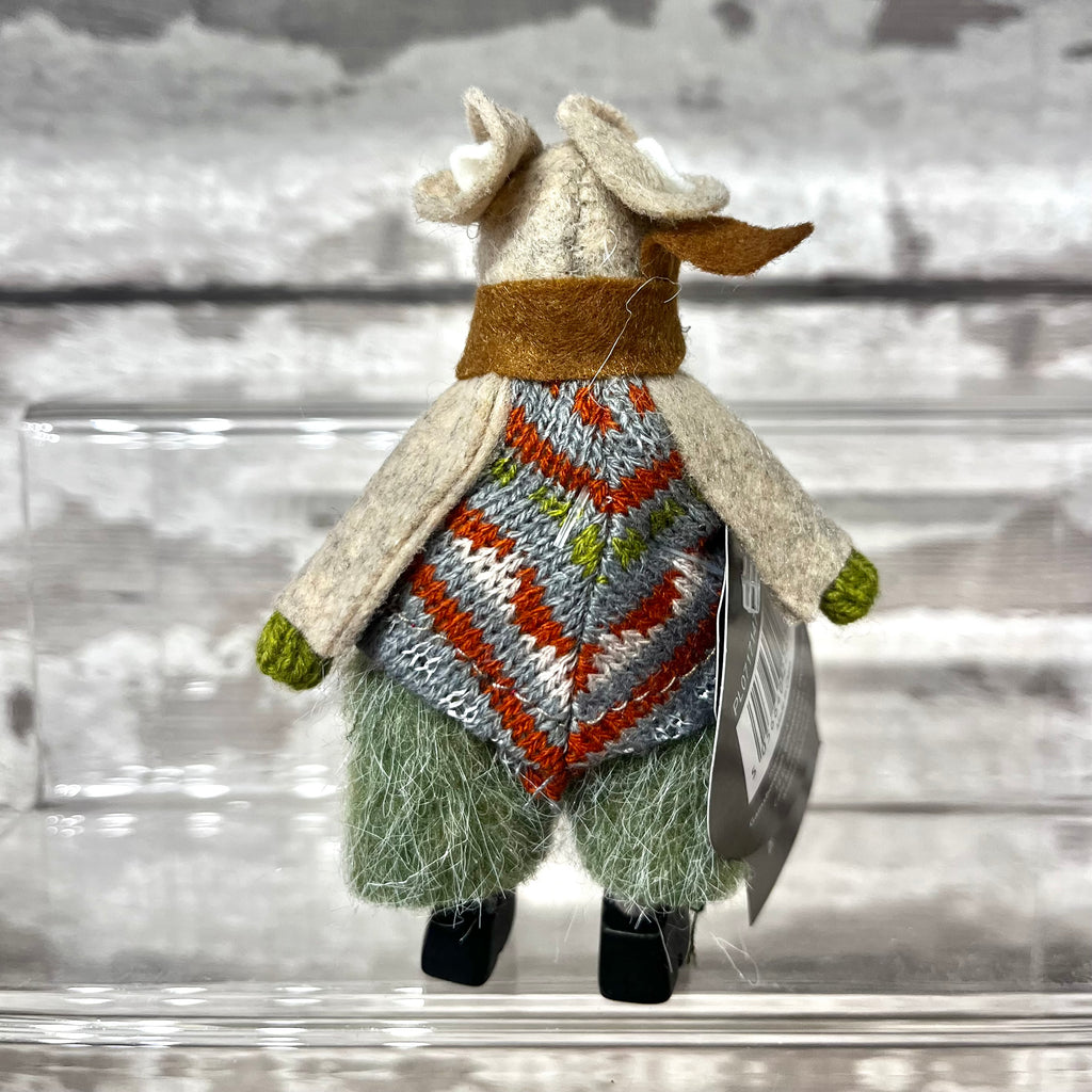 Toy mouse wearing a sweater with a pattern on a wooden surface