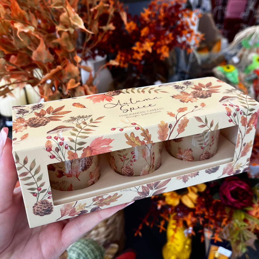Set of 3 candles in autumnal packaging with leafy autumnal background.