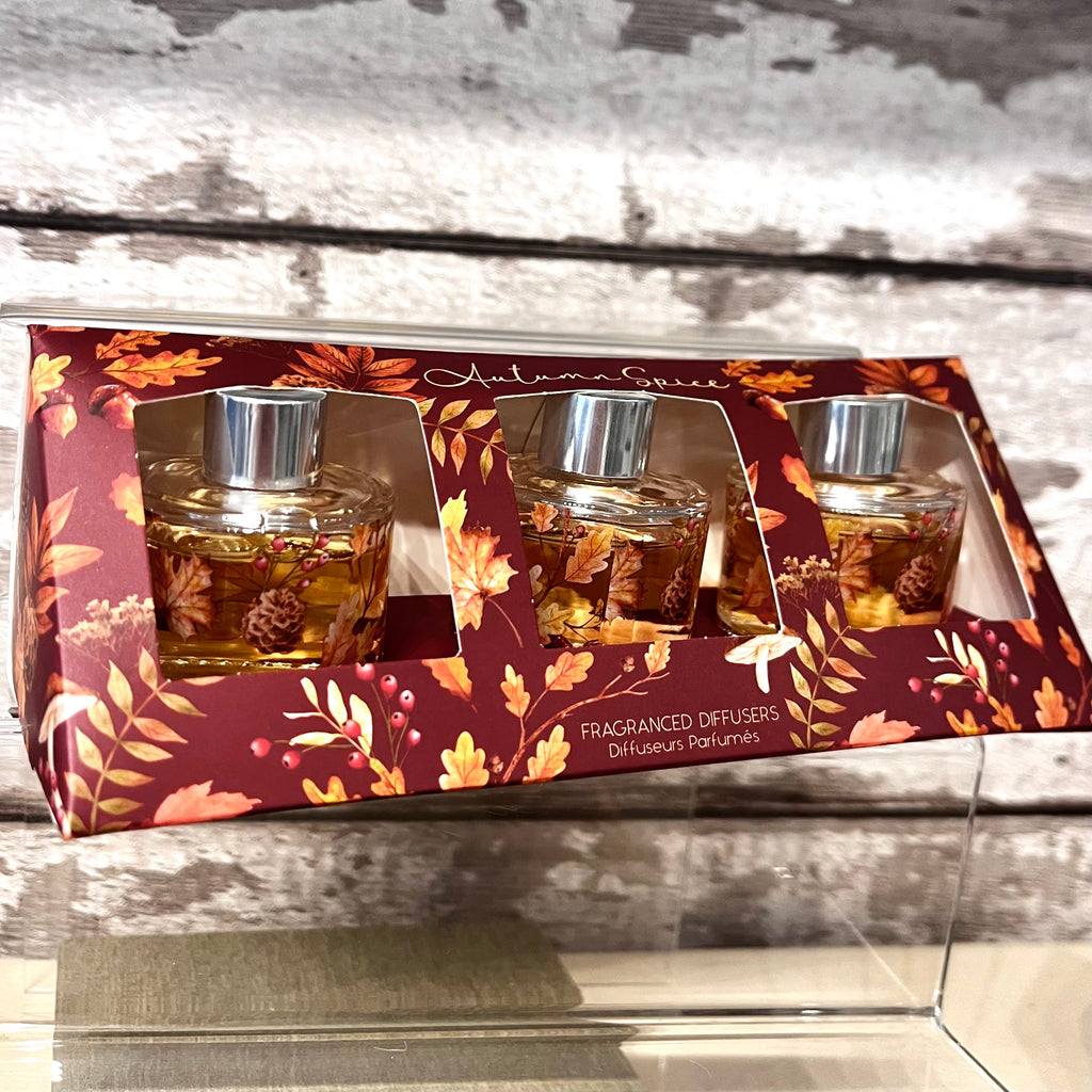 Set of three fragranced diffusers in autumnal packaging on a wooden background