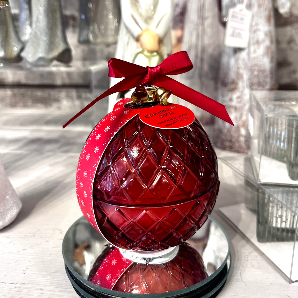 Red glass ornament with a red bow on a reflective surface