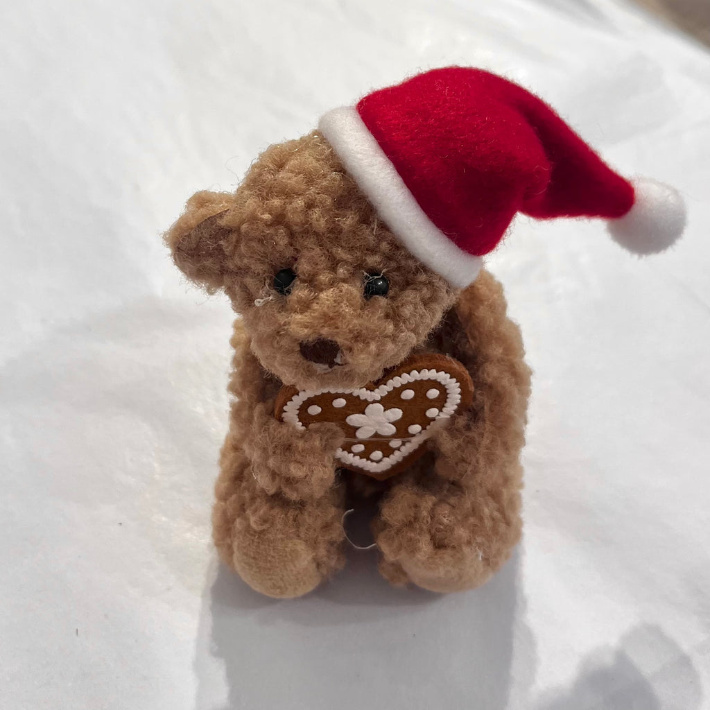 Teddy bear with santa hat and holding a gingerbread heart