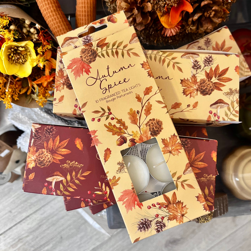 Packaging of 'Autumn Spice' tea lights with decorative design on a wooden surface.