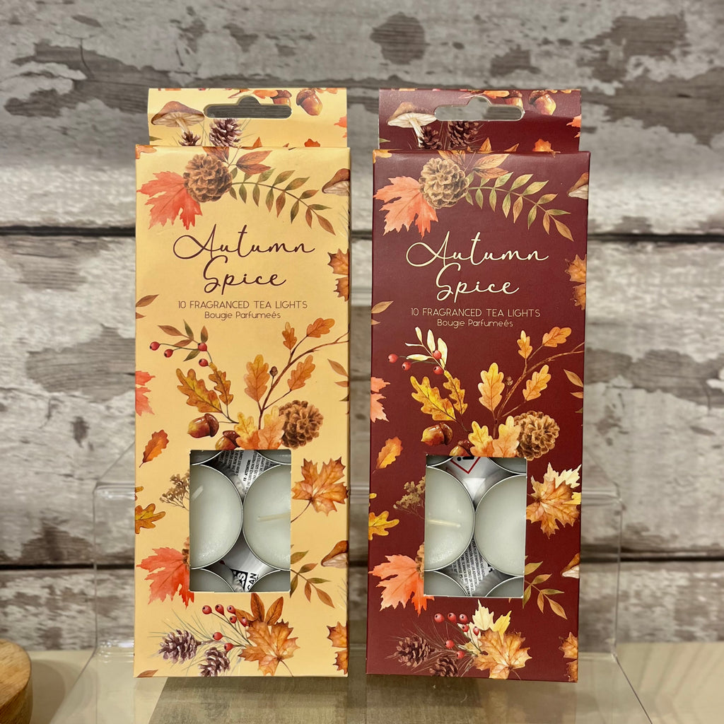 Two packages of 'Autumn Spice' scented tea lights with floral designs on a wooden surface.