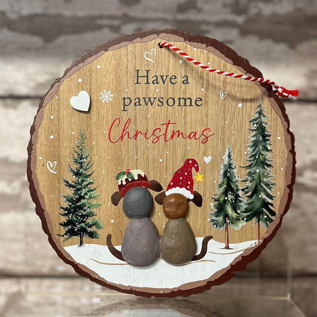 Wooden Christmas ornament with two dogs wearing hats and trees, text 'Have a pawsome Christmas'.