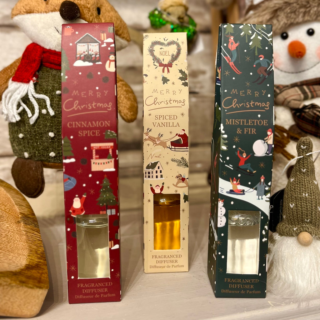 Three Christmas-themed diffuser boxes with decorative designs on a festive background.