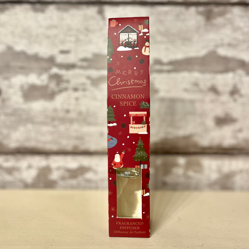 Red Christmas-themed packaging of a cinnamon spice product on a wooden surface.