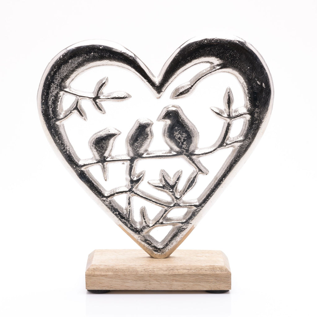 Aluminium heart on wooden base. Inside heart are a few branches. on the branch across the middle are three birds sitting,