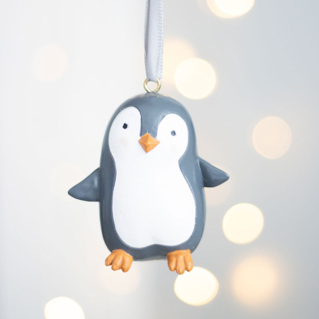 Penguin ornament hanging against a soft, blurred light background
