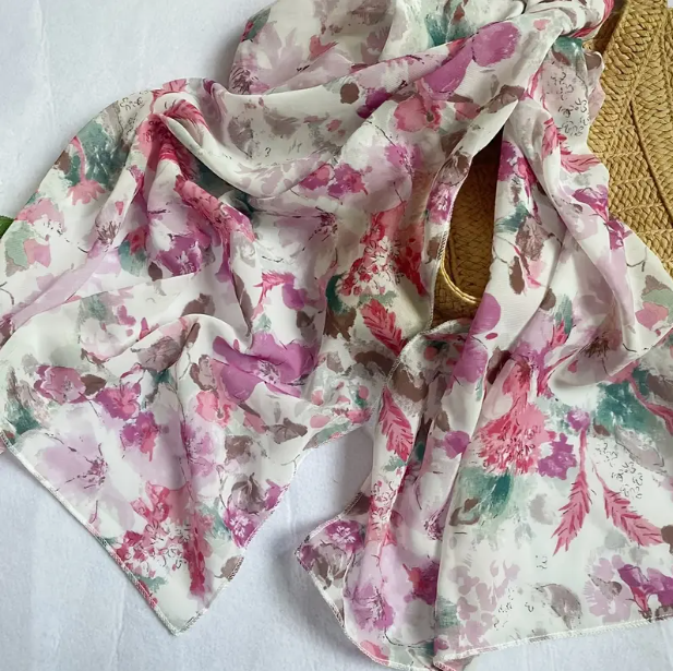 White scarf with watercolour flowers. Features cherry blossoms along with other darker pink flowers.