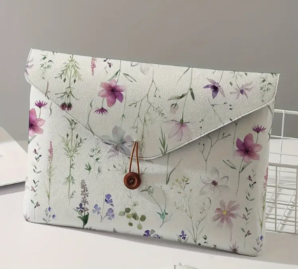 White laptop sleeve with purple flowers and green stems and leaves. Brown wooden button with loop fastener.