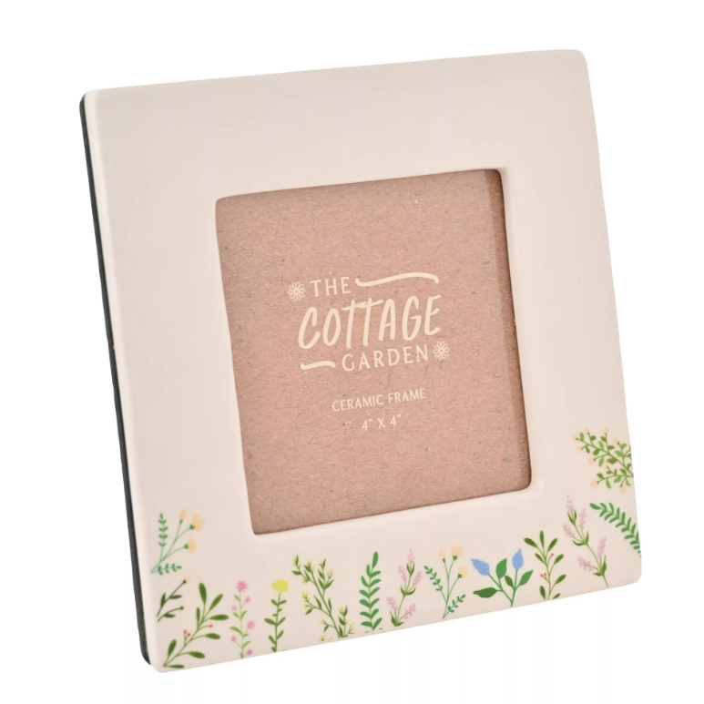 Square cream photo frame with thick border. On the bottom of the frame is leaves and flowers on stems in a minimalist design in light blues and pinks and yellows. 
