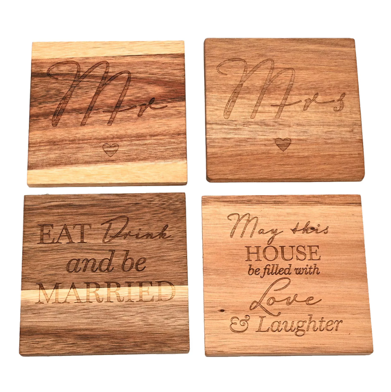 Set of four wooden coasters featuring four different designs. One coaster with 'Mr' engraved is big script font, one with 'Mrs' engraved in big script font, one engraved with 'eat, drink, and be married', and the last one engraved with 'may this house be filled with love & laughter'.