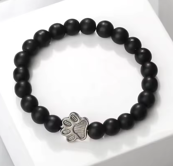 Black beaded bracelet with a silver paw print charm on a white background