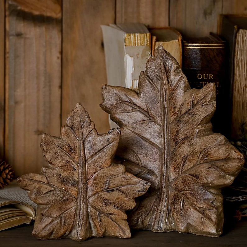 two wooden leaf decorations of different sizes on a rustic wooden background
