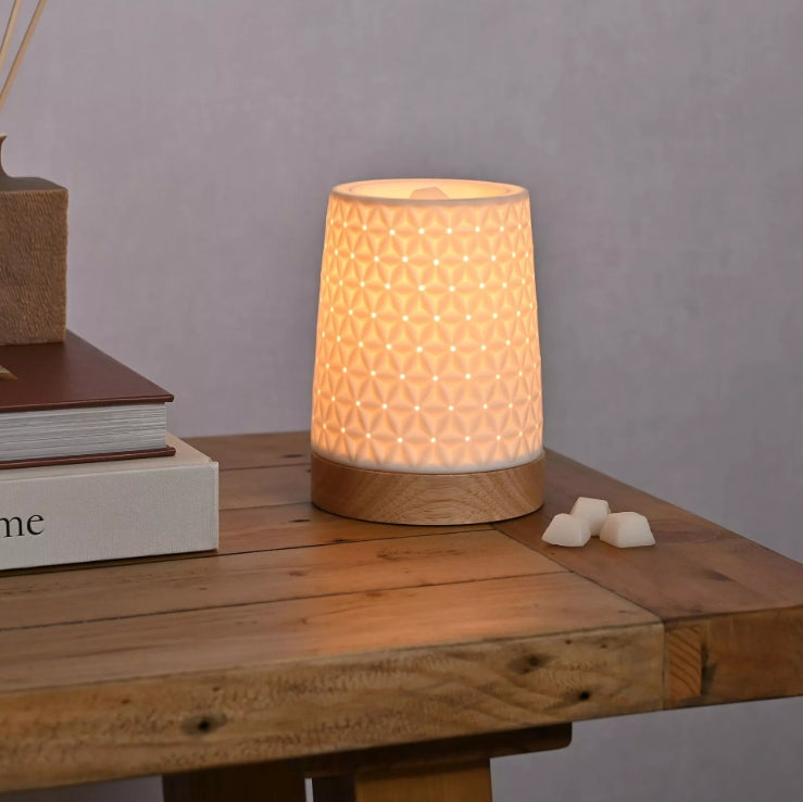 Lamp with textured design on a wooden surface with books and small objects.
