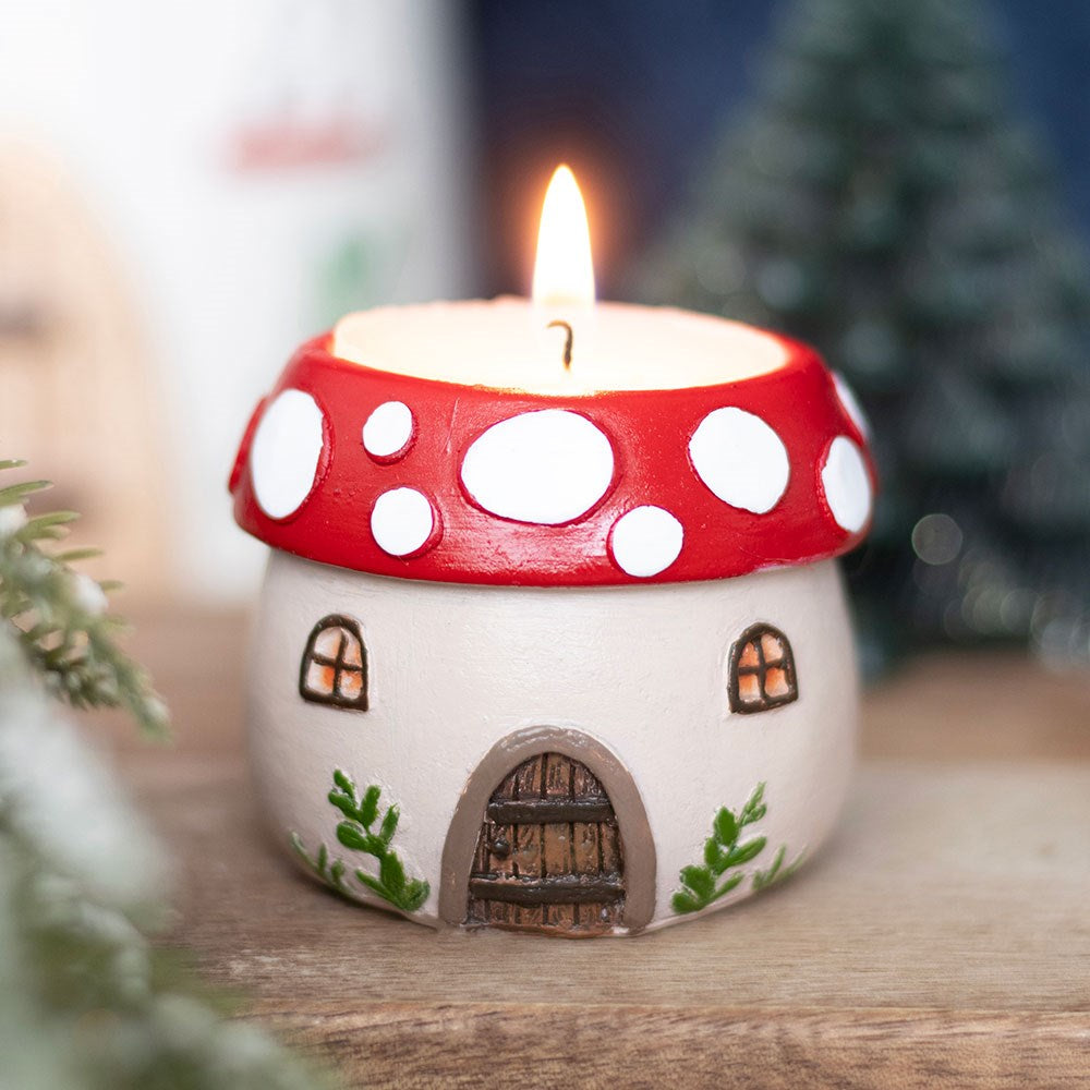 Mushroom house tealight holder with cream base featuring a arched door and windows, and a red top with white spots.