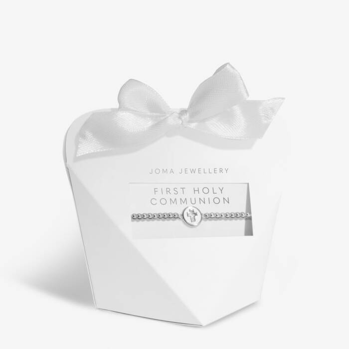 Silver bracelet with silver cross charm packaged in a love heart shape box with a white ribbon bow at the top. Features the test 'First Holy Communion' in silver above the bracelet. 