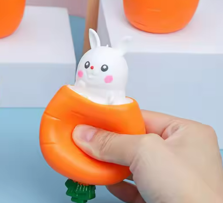 cartoon carrot stress ball squeezed with a white rabbit popping out the top
